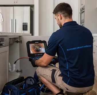 Plumber clearing a blocked toilet in a Erskineville bathroom